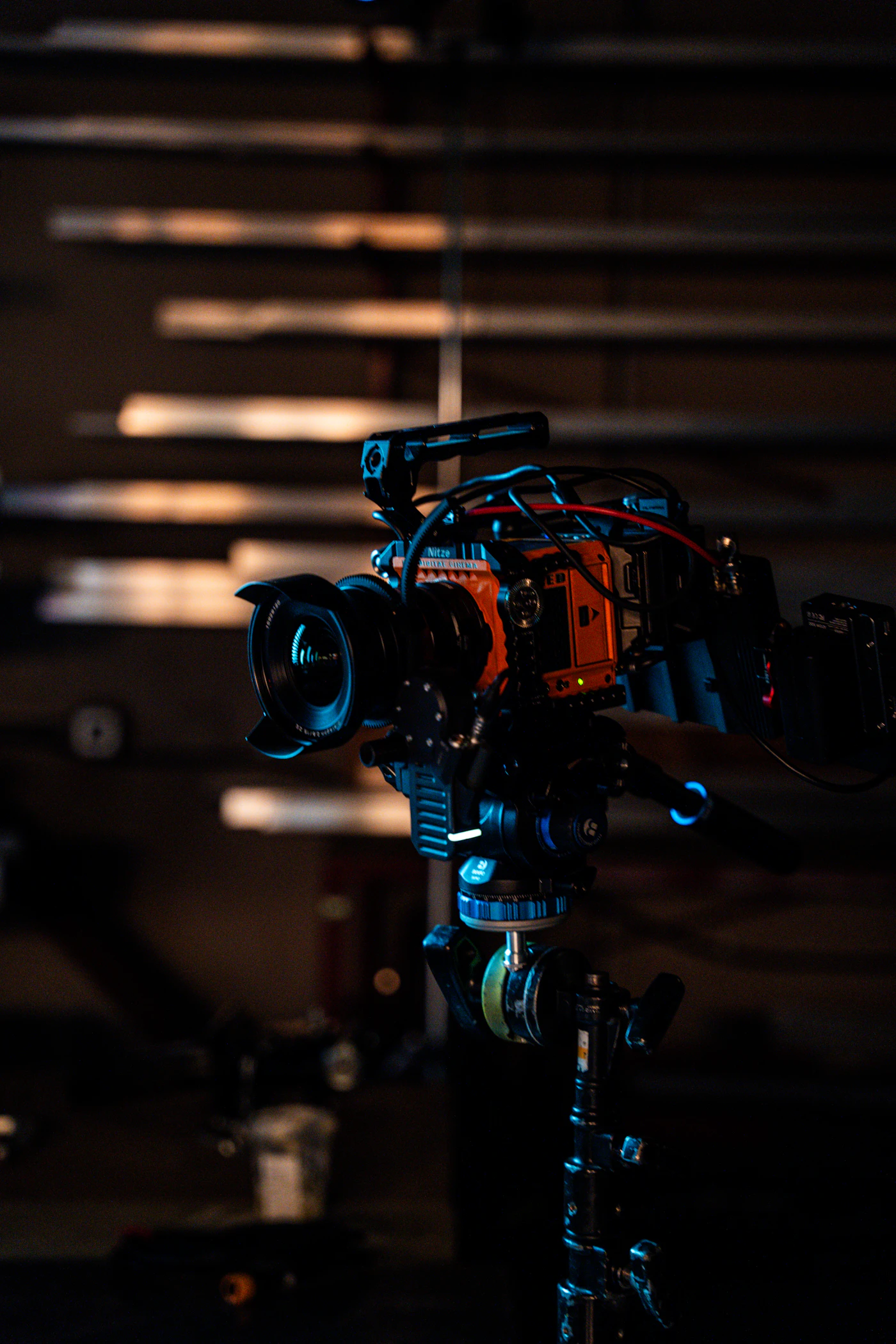 A complex cinema camera rig bristling with lenses, cables, and mounting hardware on a dark set — the machinery behind the image, not the face in front of it.