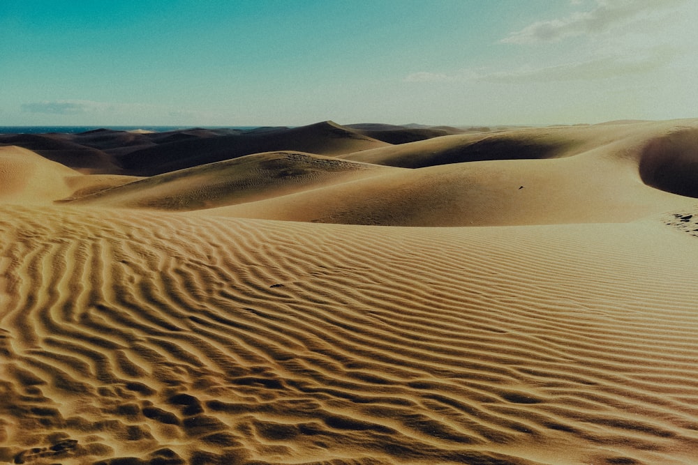 a desert landscape with sand dunes and blue sky