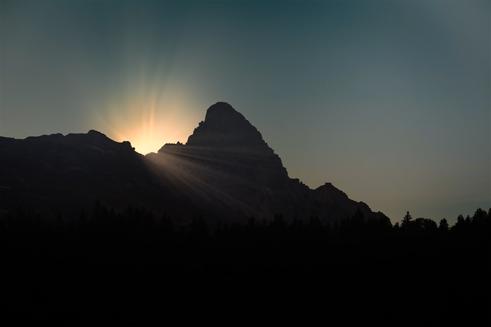 the sun is setting behind a mountain peak