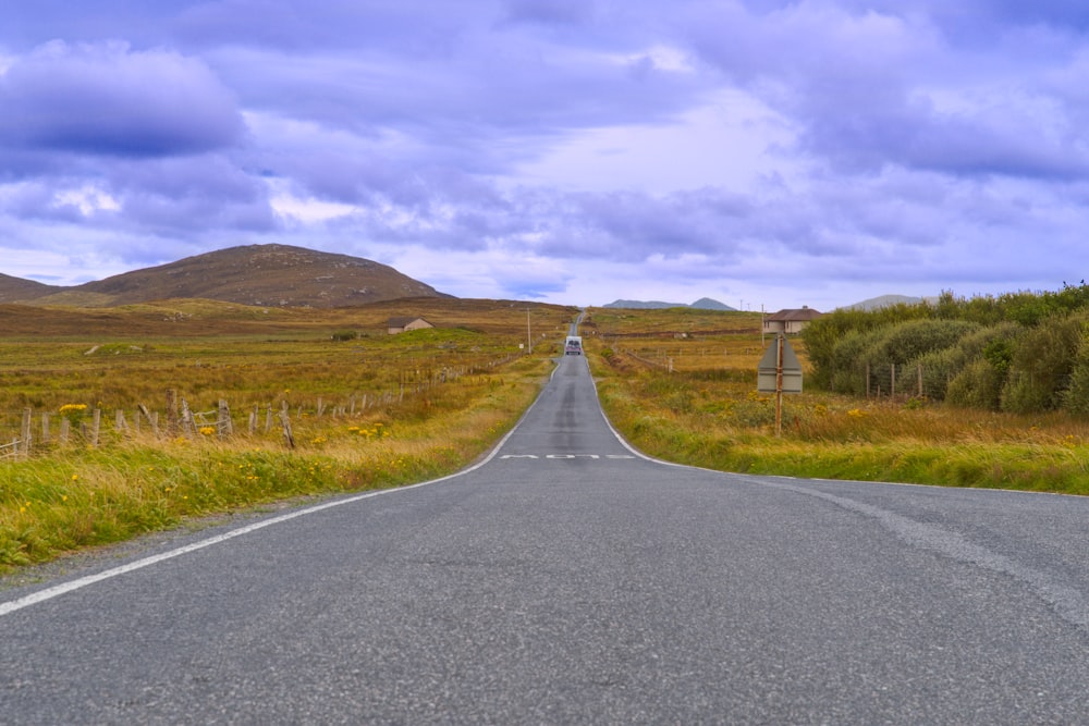 an empty road in the middle of a field