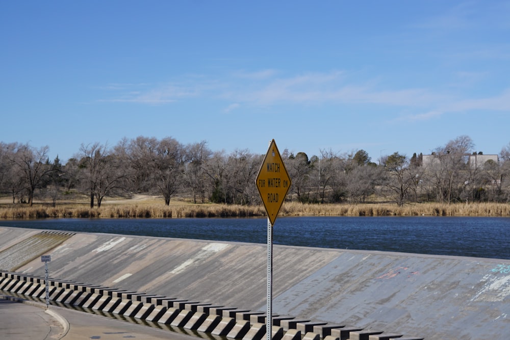 a yellow street sign sitting on the side of a river