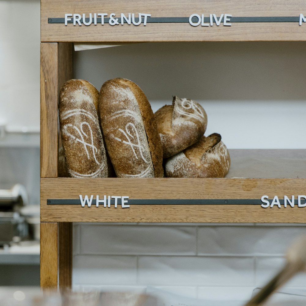 breads are displayed on a shelf in a bakery