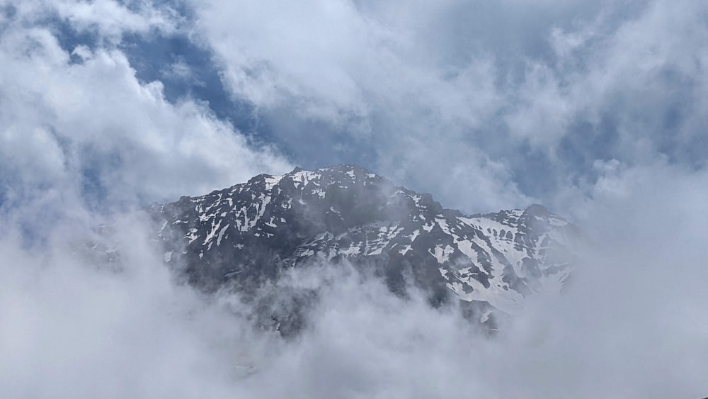 una montagna coperta di neve e nuvole sotto un cielo nuvoloso