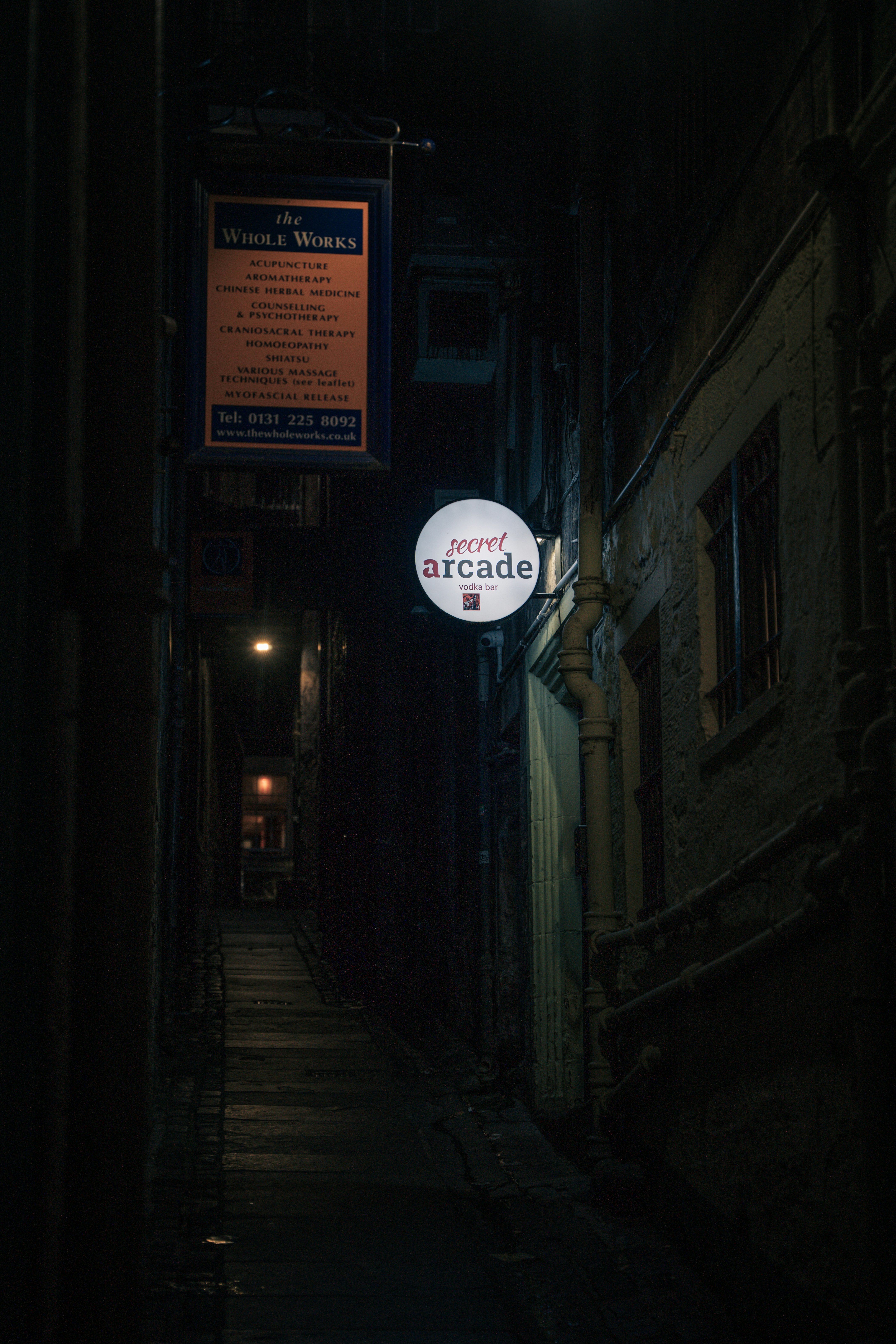 a dark alley way with a sign hanging off the side of it