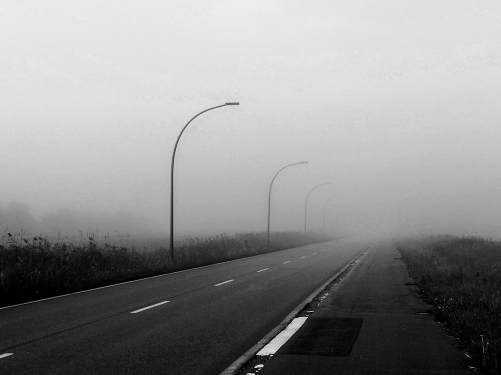 a foggy road with street lights and street signs