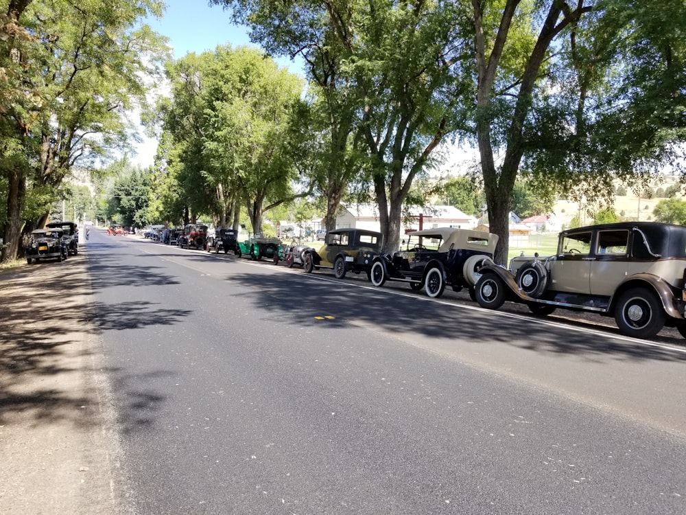 a row of antique cars parked on the side of a road