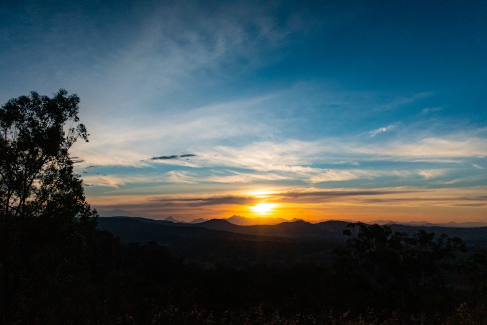 the sun is setting over the mountains in the distance