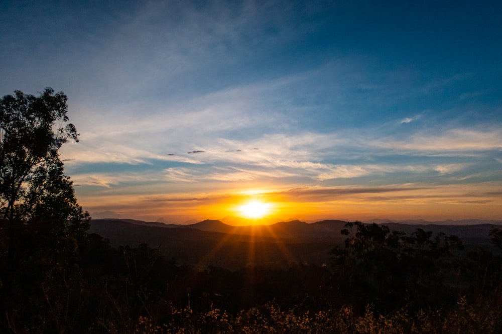 the sun is setting over a mountain range