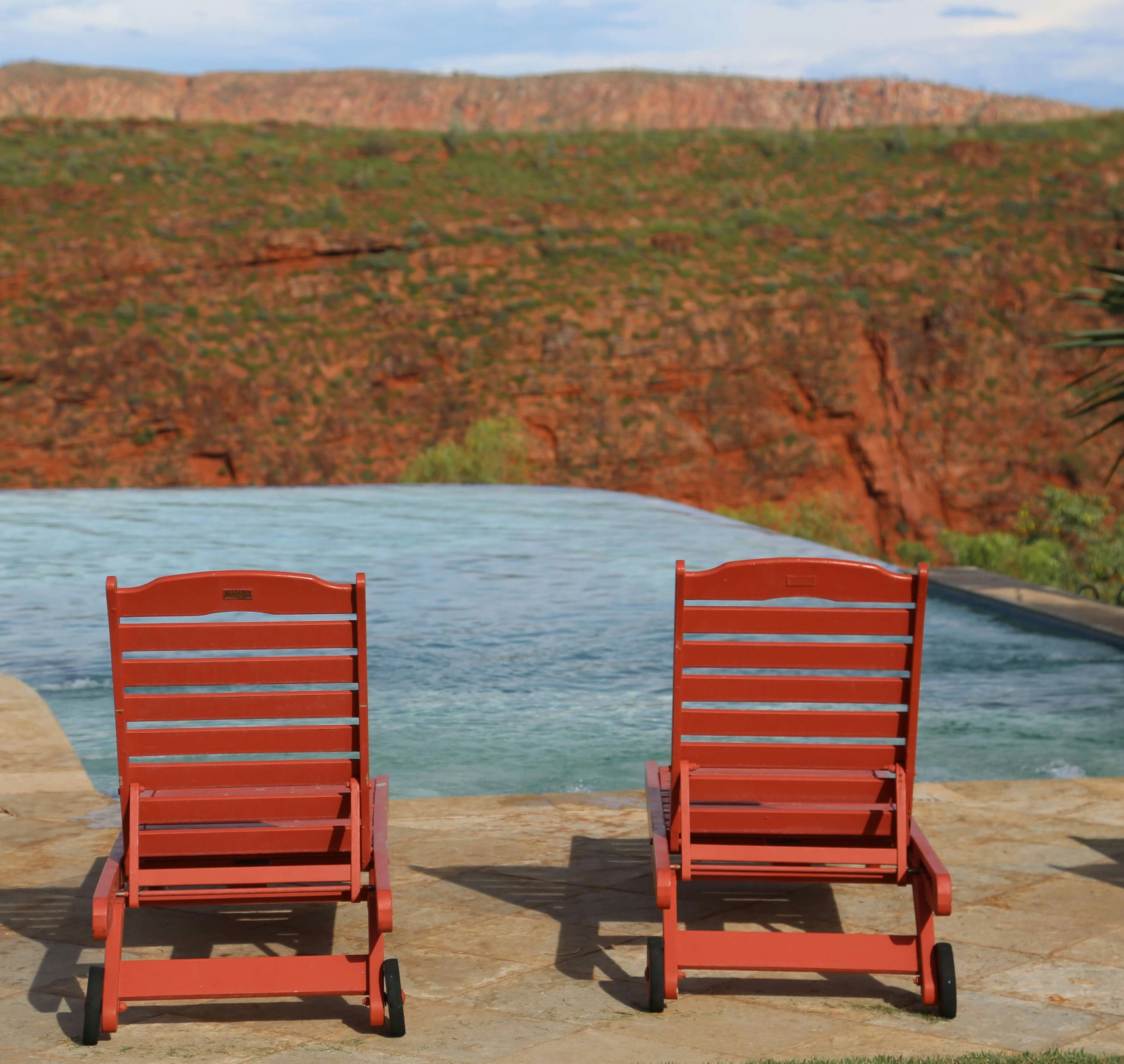 A couple of red chairs sitting next to a pool photo – Free Brown Image ...