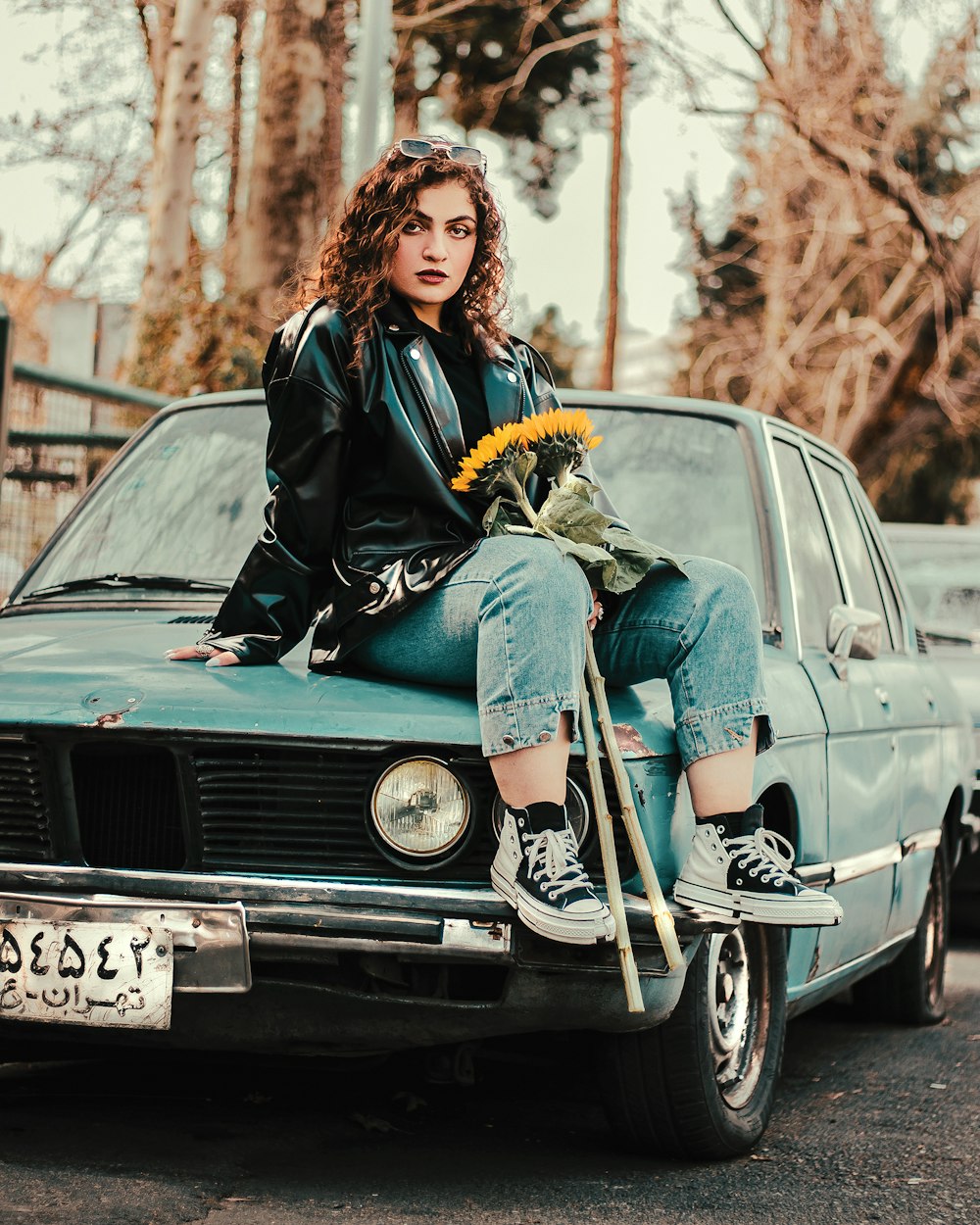 a woman sitting on the hood of a car