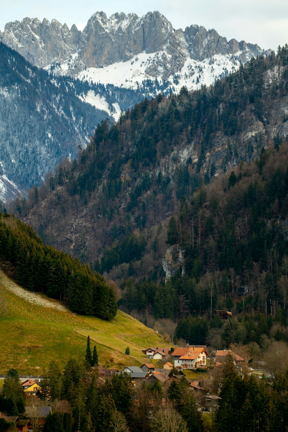 a village nestled in the mountains with snow on the mountains