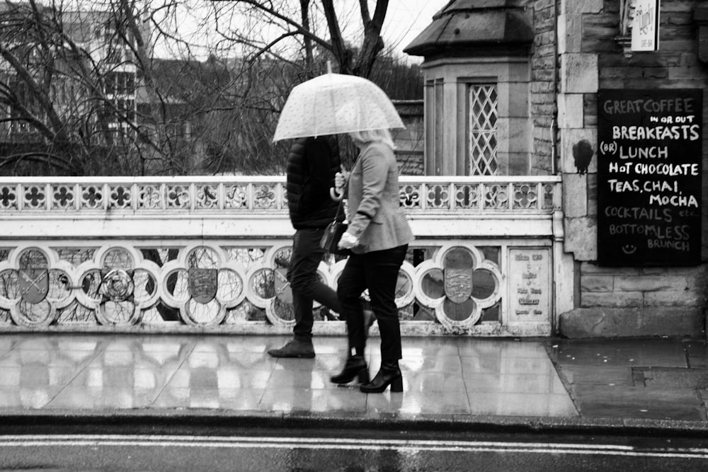 ein Mann und eine Frau, die mit einem Regenschirm eine Straße entlang gehen