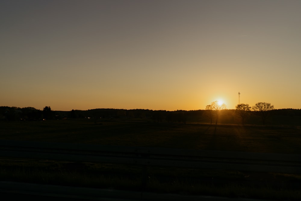 the sun is setting over a grassy field