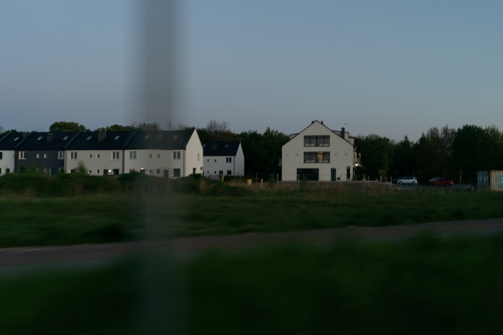 a row of white houses sitting next to a lush green field