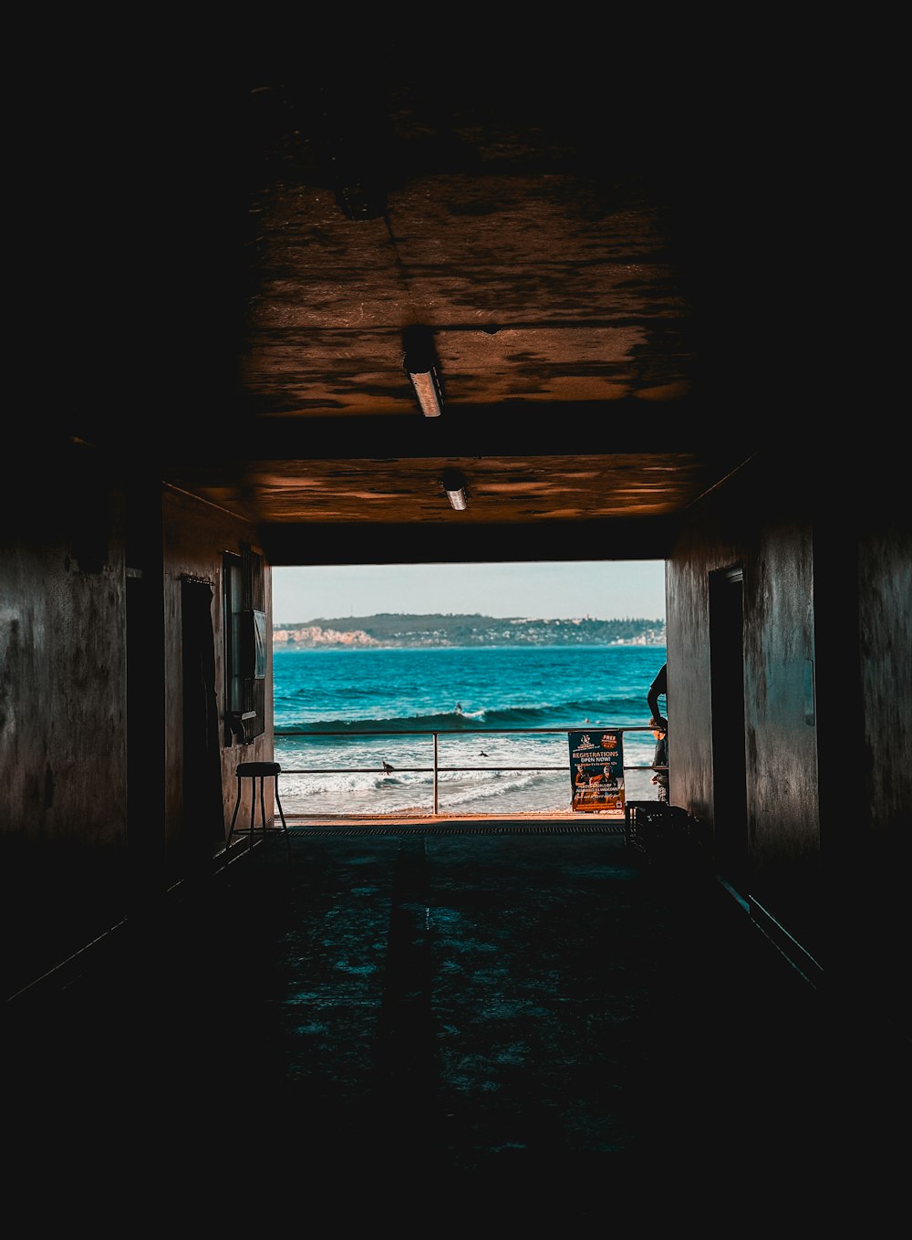 a person standing in a doorway looking out at the ocean