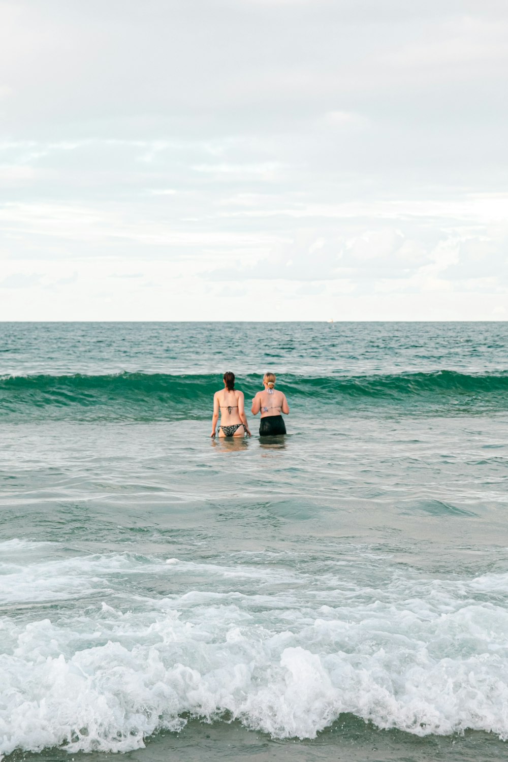 a couple of people standing in the ocean