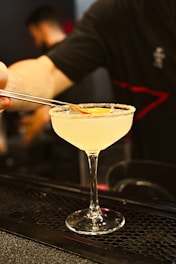 a person is holding a spoon over a martini