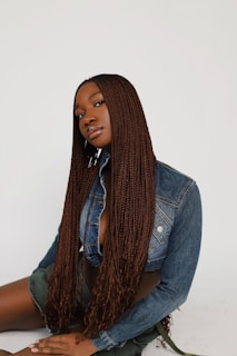 a woman sitting on the ground wearing a jean jacket