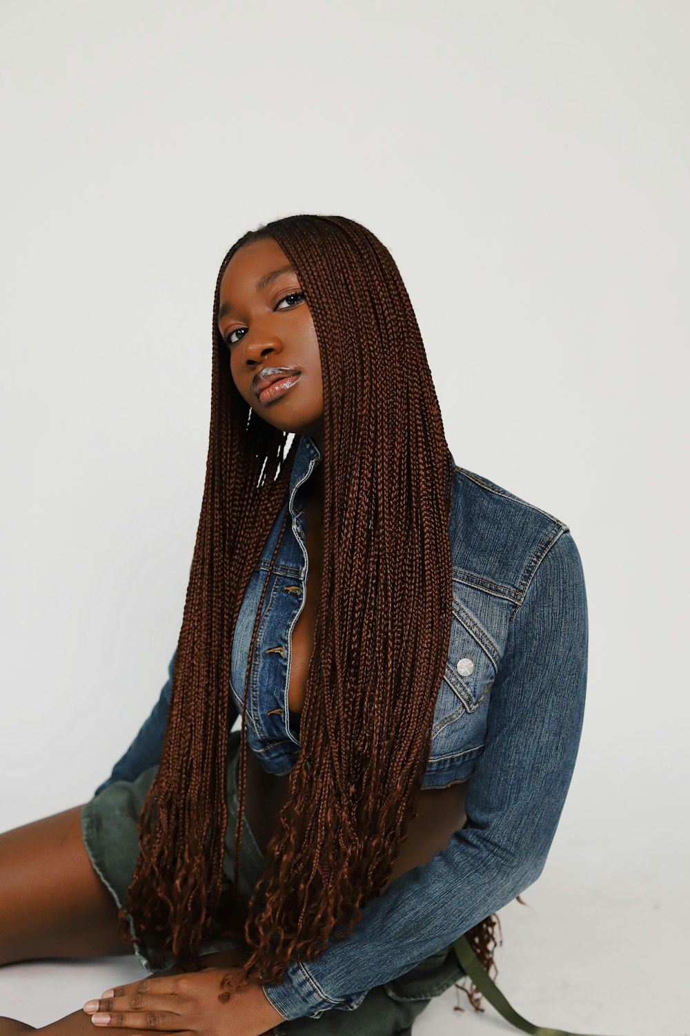 a woman sitting on the ground wearing a jean jacket