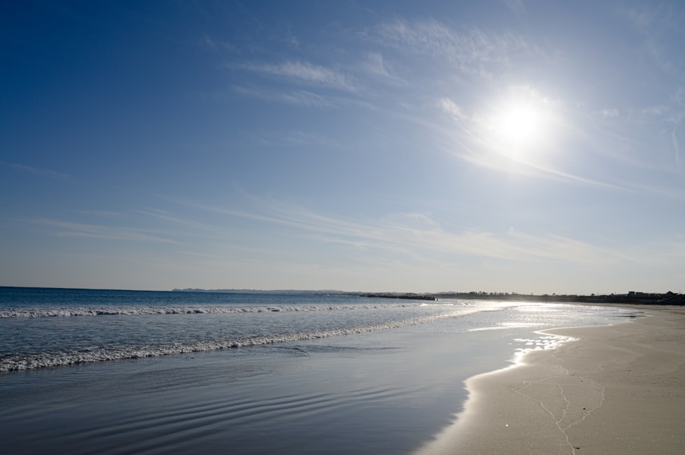 the sun is shining over the water at the beach