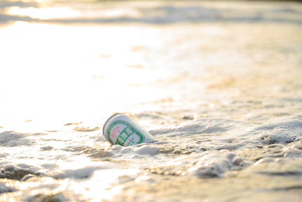 une canette de soda posée sur une plage de sable