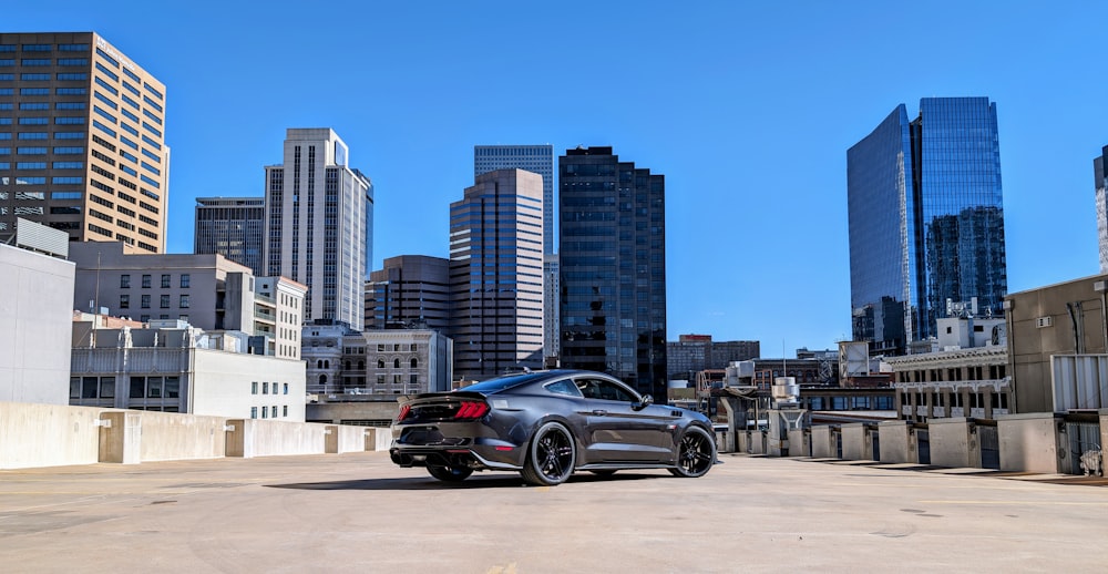 a car parked in a parking lot in front of tall buildings