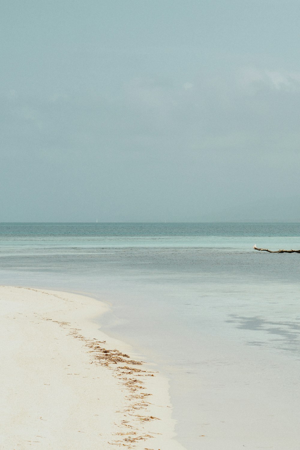 a lone boat sitting on the shore of a beach
