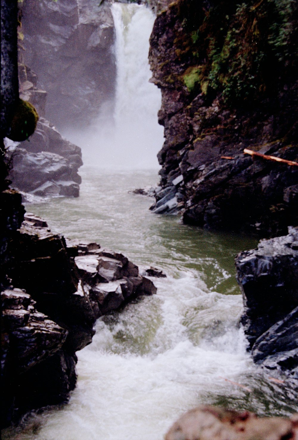 a man standing on top of a rock next to a waterfall