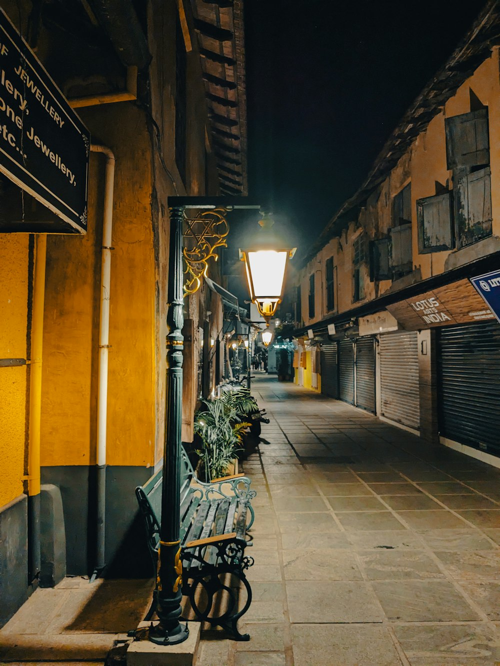 a bench sitting on the side of a street next to a lamp post