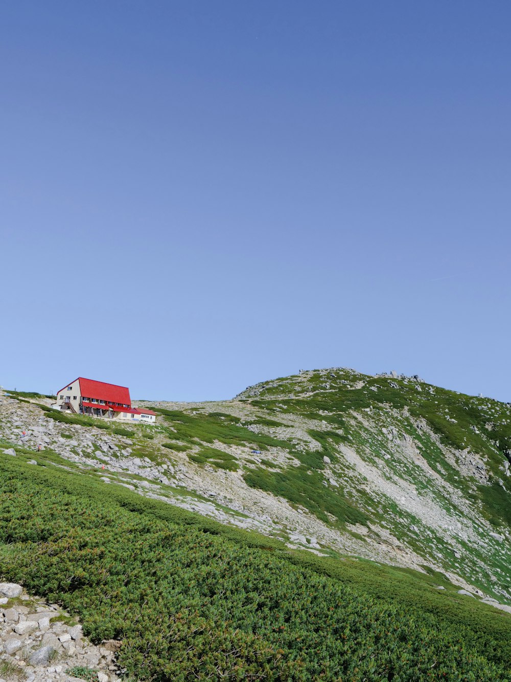 a red house sitting on top of a lush green hillside