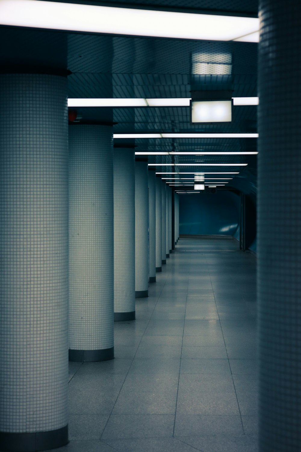 a long hallway with columns and lights on either side