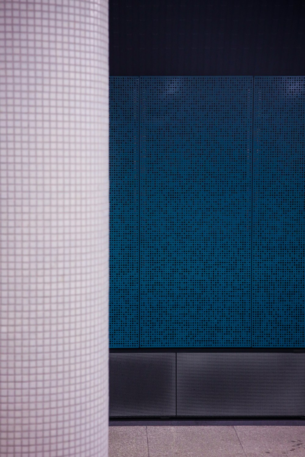a blue tiled wall next to a white pillar