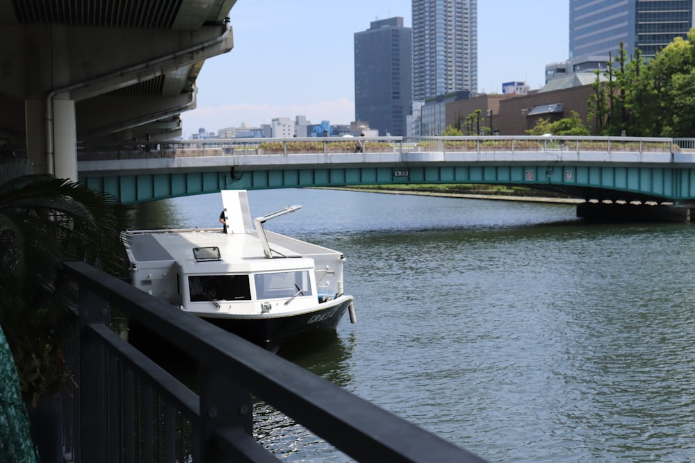 a white boat floating on top of a river under a bridge