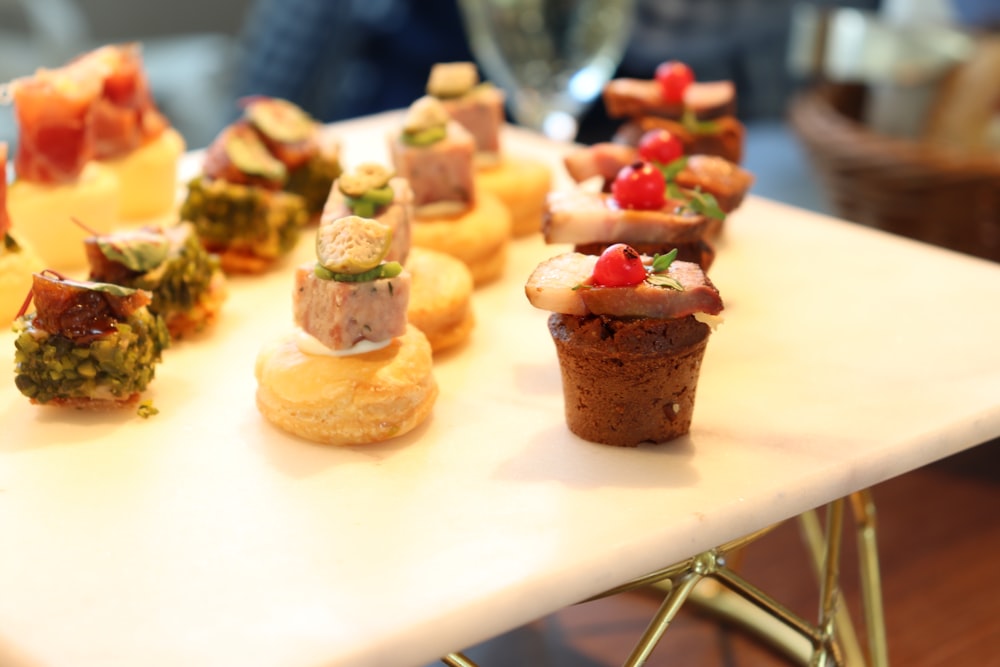 a white table topped with small cupcakes covered in toppings