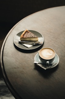 a piece of pie on a plate next to a cup of coffee