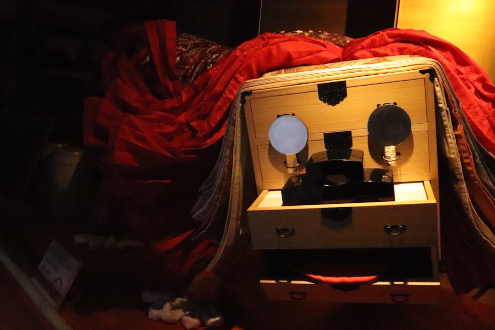 a wooden box sitting on top of a bed covered in red sheets