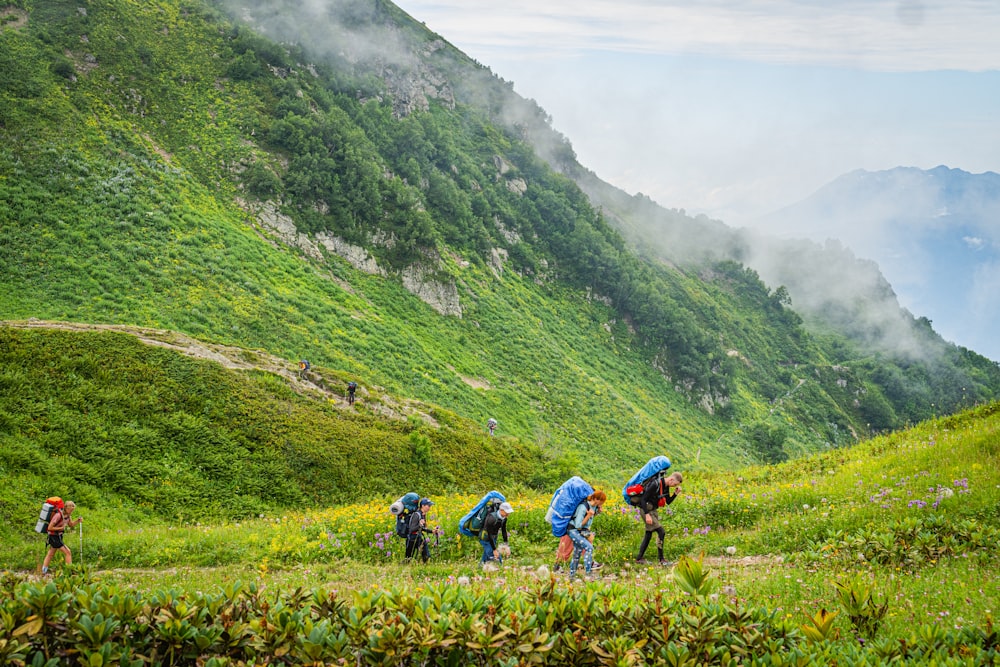 a group of people with backpacks hiking up a hill