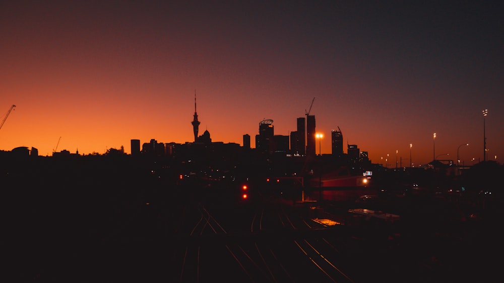 a city skyline at night with a train on the tracks