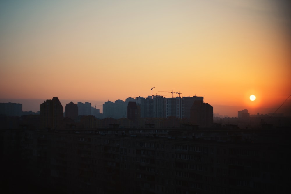 the sun is setting over a city with tall buildings