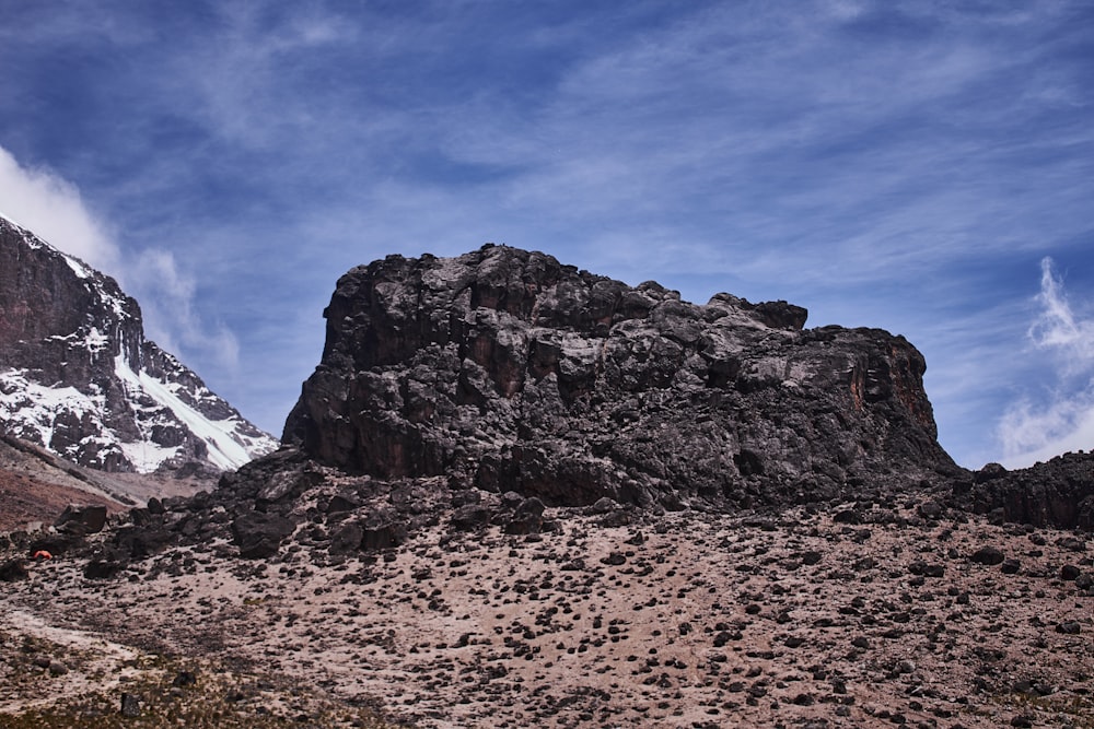 a rocky mountain with a snow capped mountain in the background