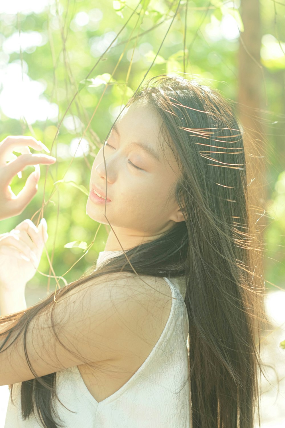 a woman with long hair standing under a tree