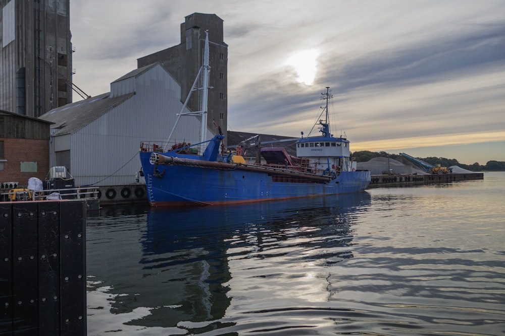 a large blue boat in the water next to a building