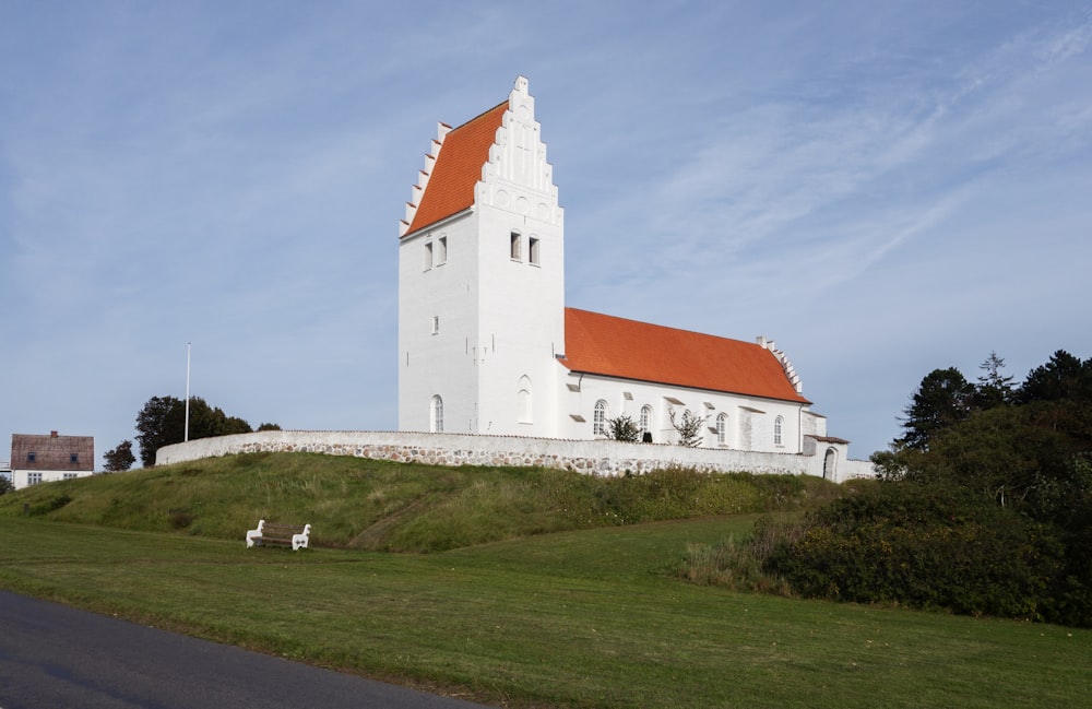a white church with a red roof on a hill