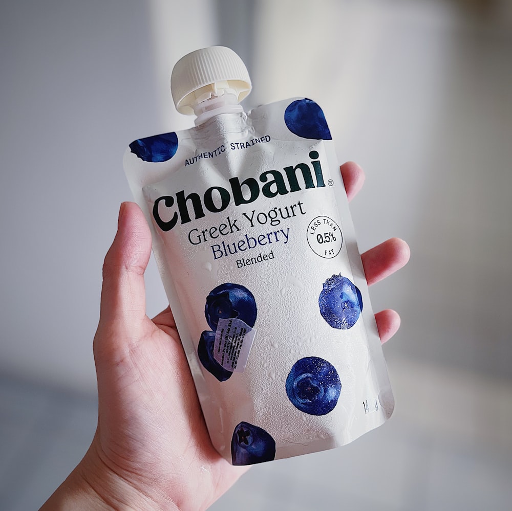 a hand holding a bottle of chobani greek yogurt blueberry
