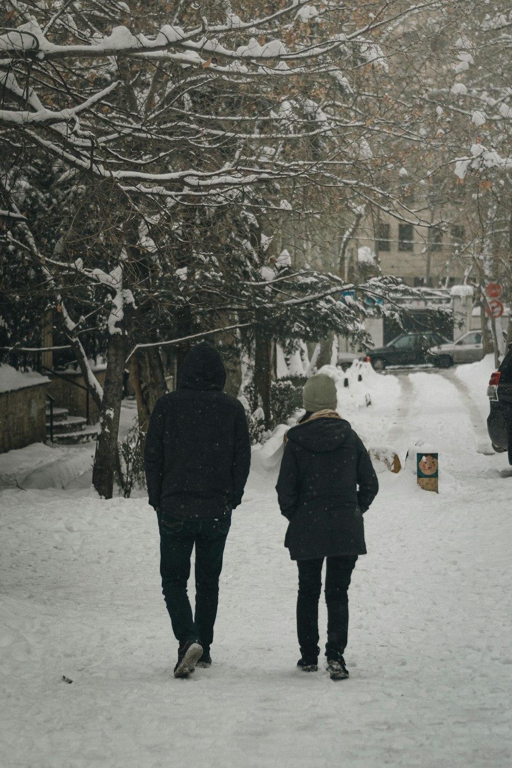 two people walking down a snow covered street