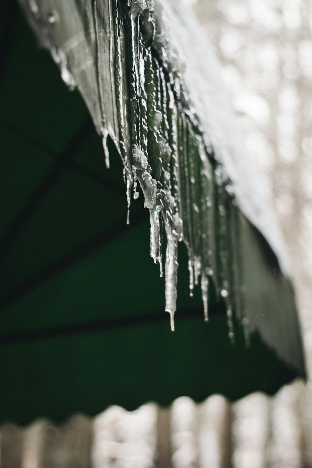 a green umbrella covered in ice and icicles