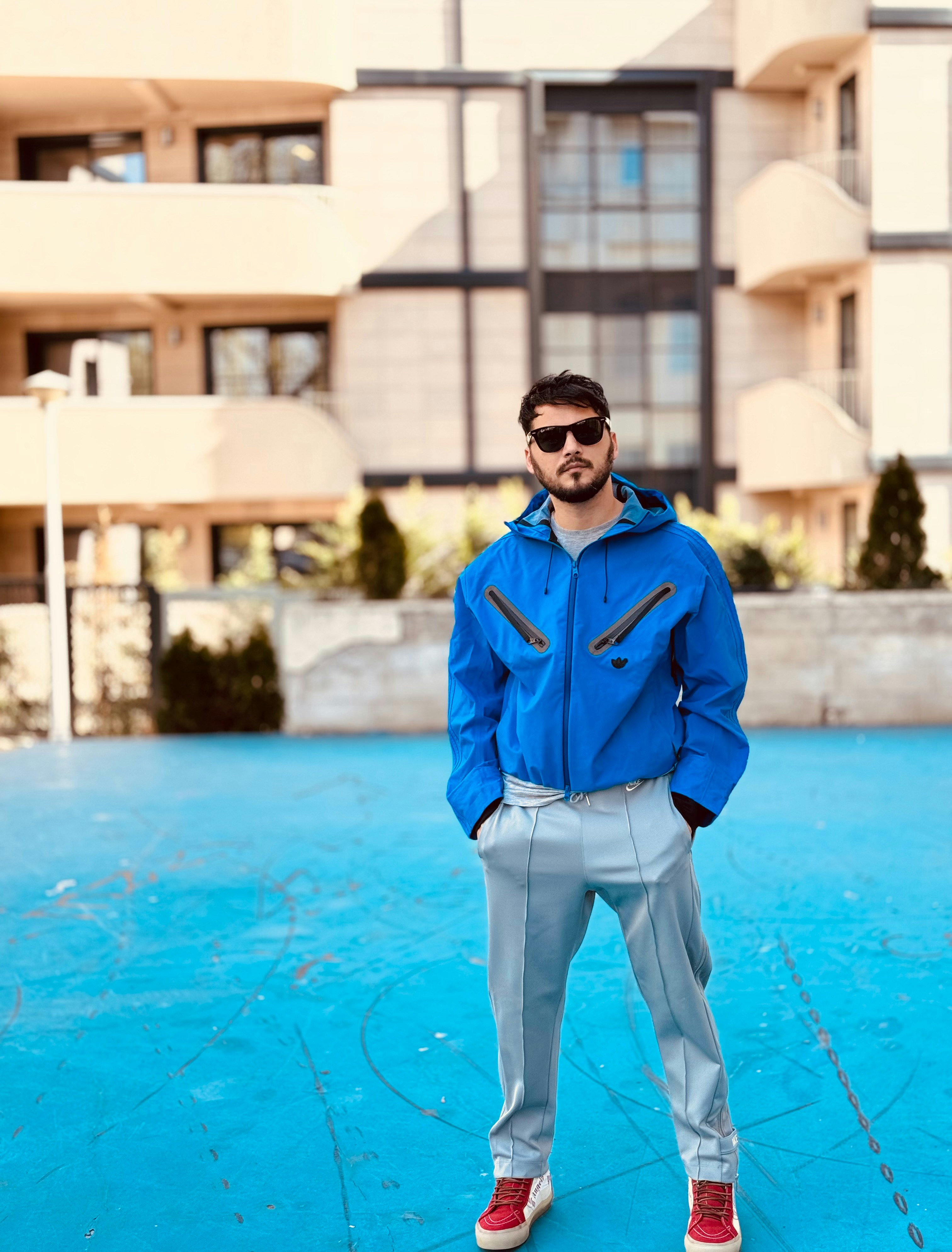 a man in a blue jacket standing in front of a building