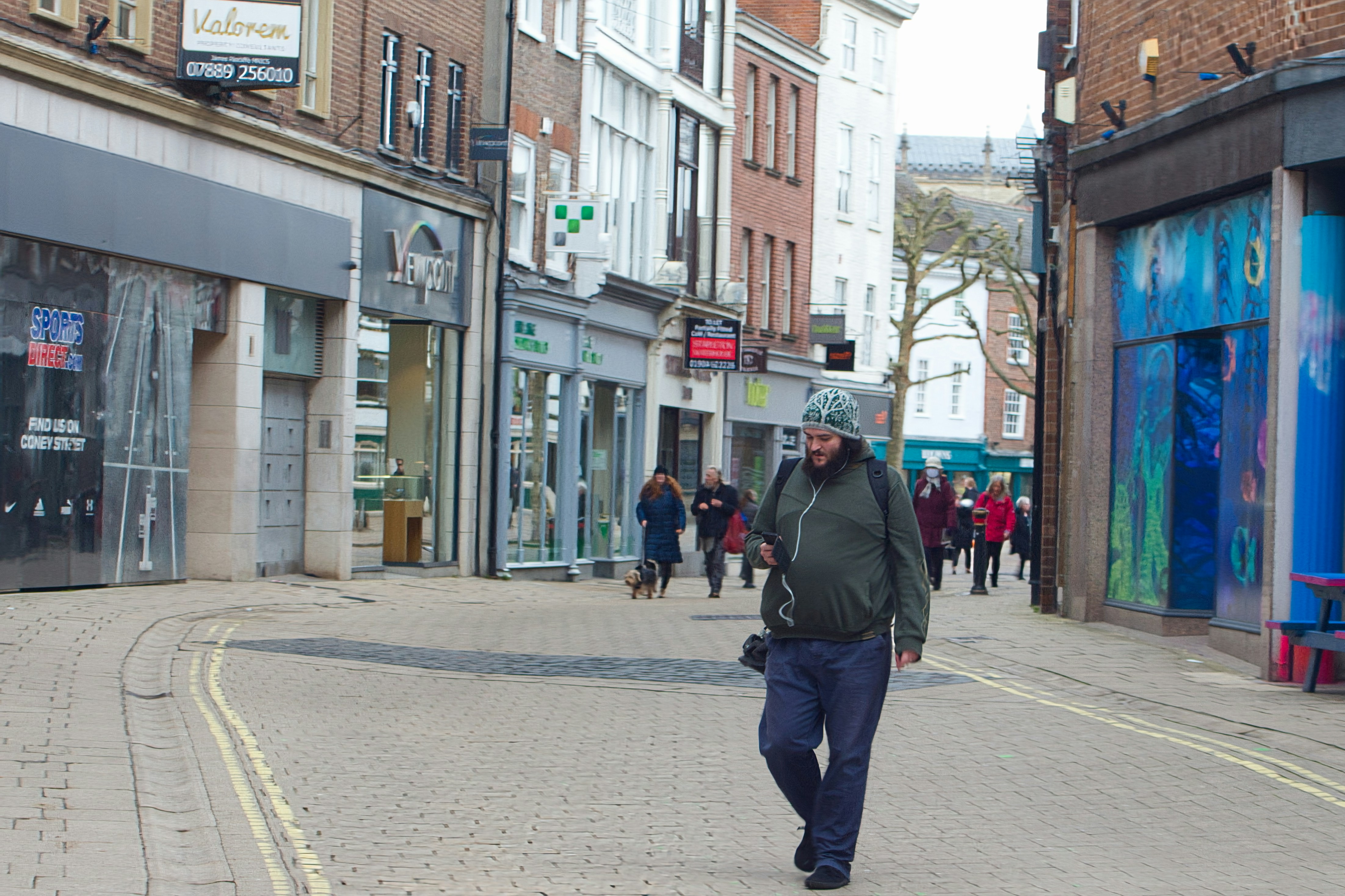 a man walking down a street next to tall buildings