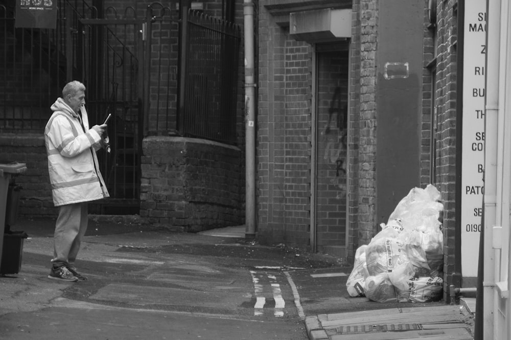 a man standing on the side of a road next to a trash can