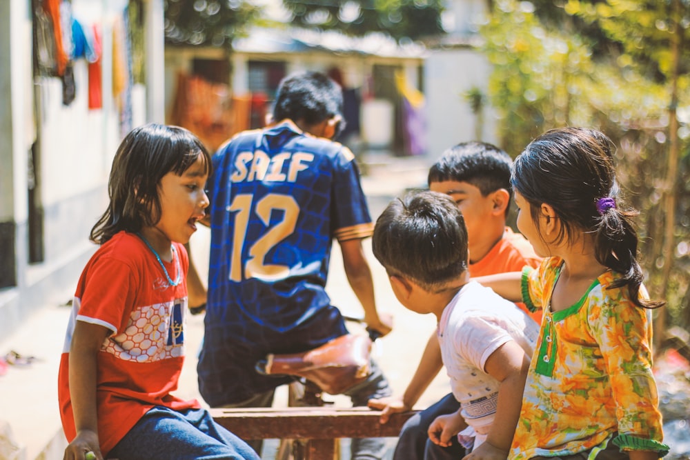 Un grupo de niños sentados alrededor de una mesa de madera